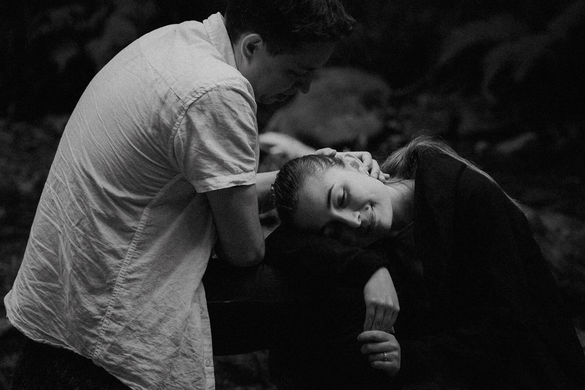 A black and white photo of a couple hugging in the dark.