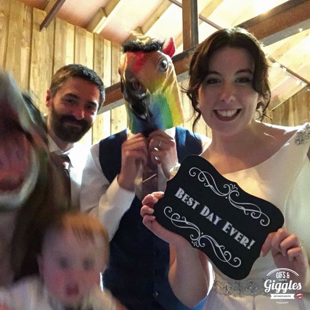 A group of people holding up a sign with a horse on it at a wedding gifbooth.