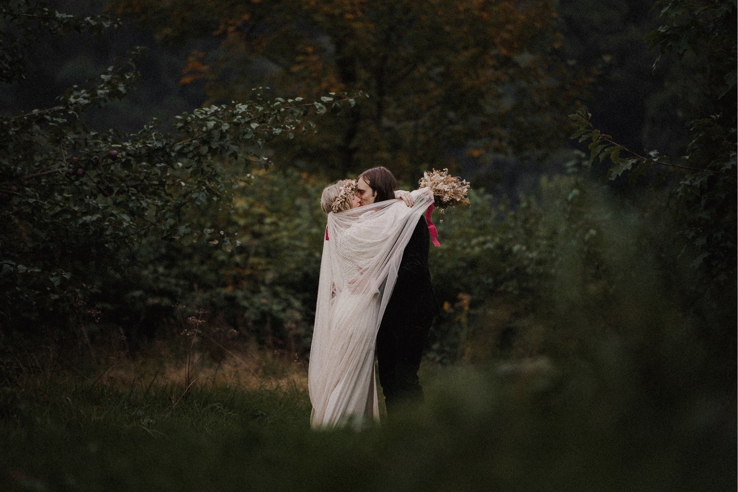 Wedding photographs of a bride and groom hugging in an orchard.