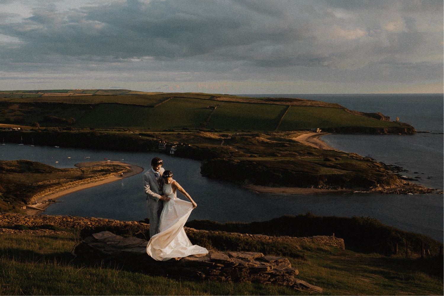 Wedding Photographs capturing a bride and groom atop a hill with an ocean view.