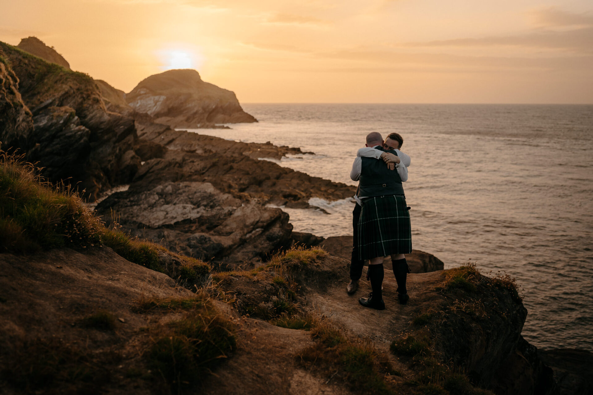 A couple's recent wedding ceremony on a cliff overlooking the ocean at sunset.