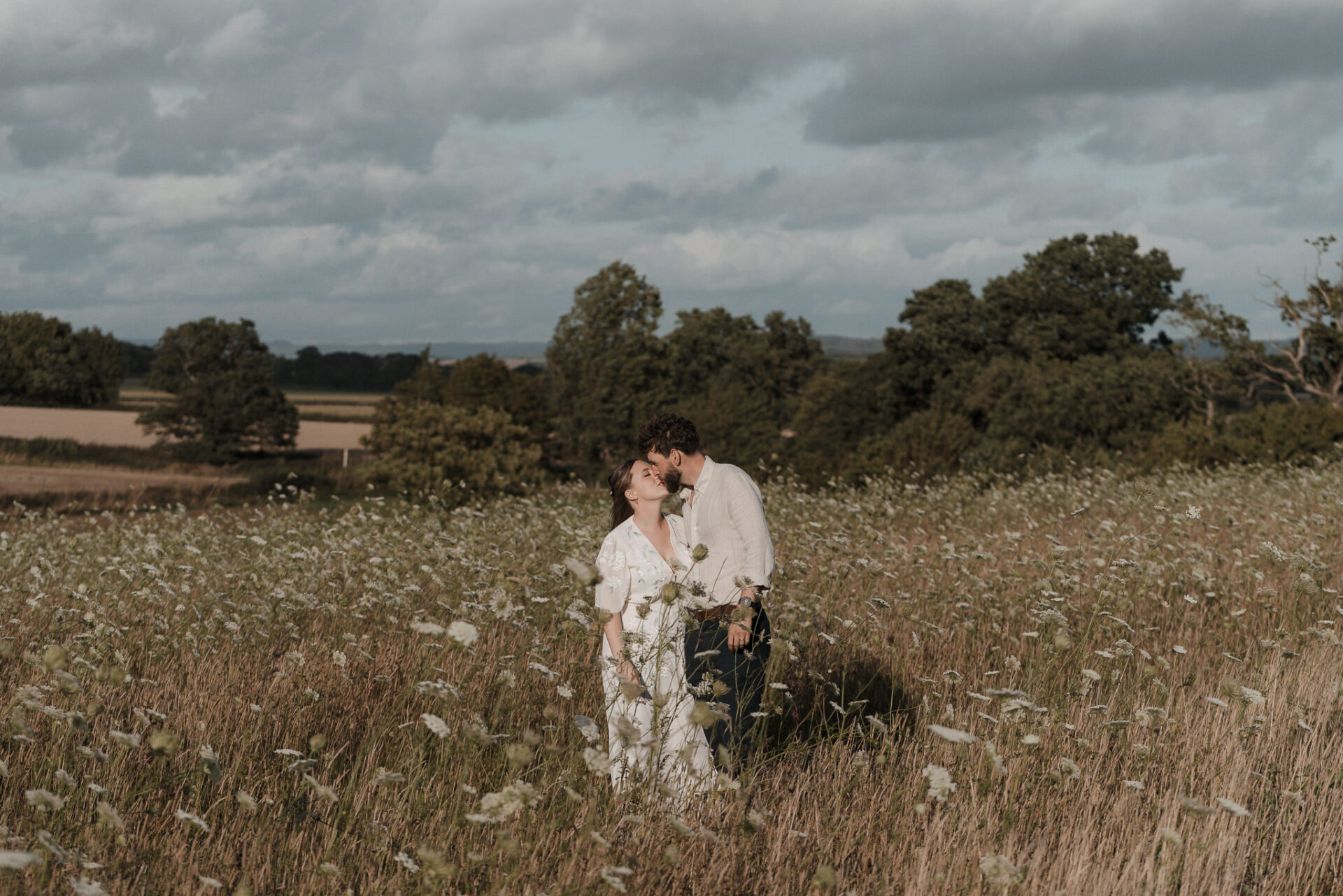 A bride and groom sharing a sweet kiss in a picturesque field of wildflowers at their recent wedding.