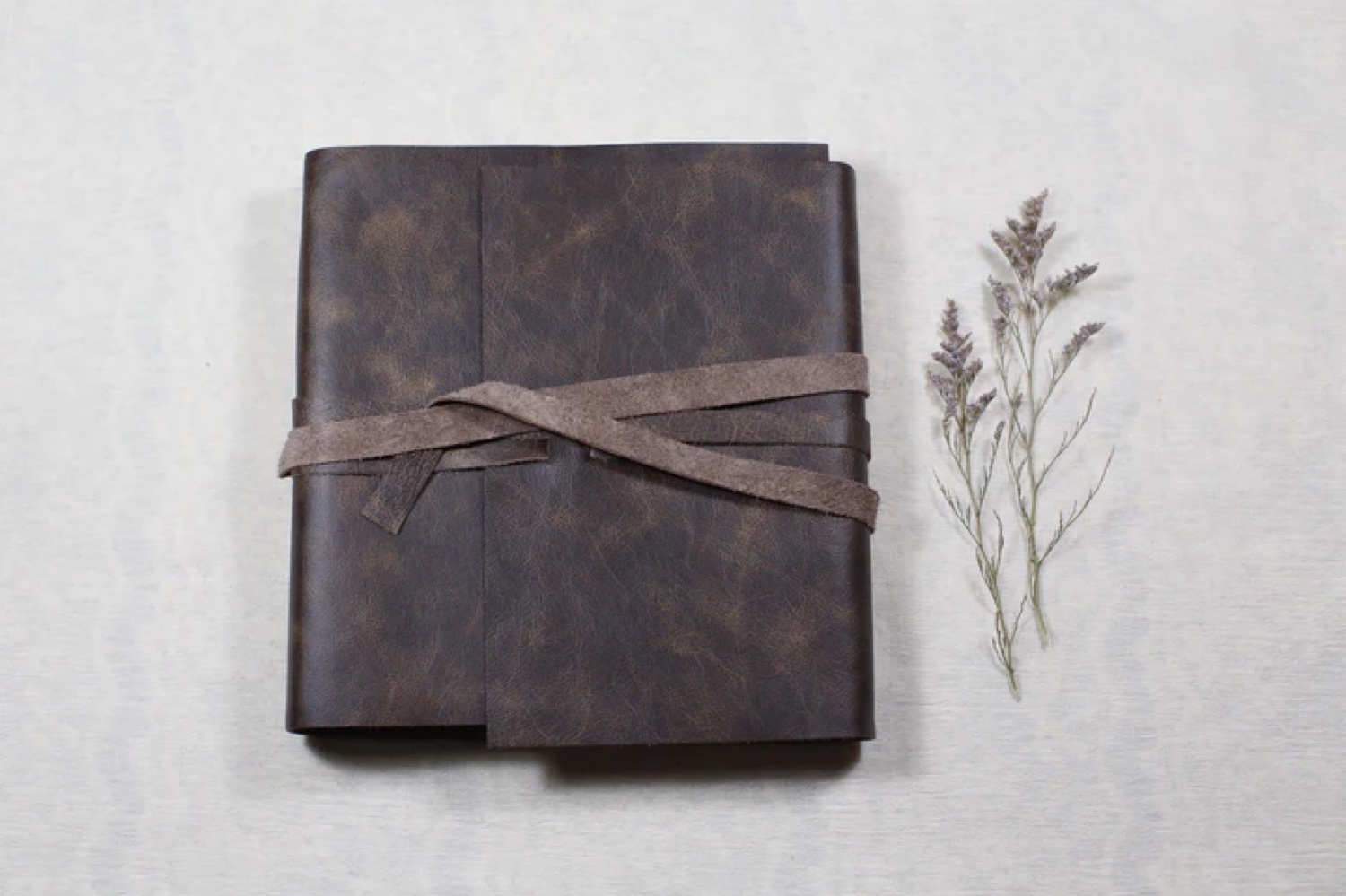 A brown leather journal with a ribbon tied around it.