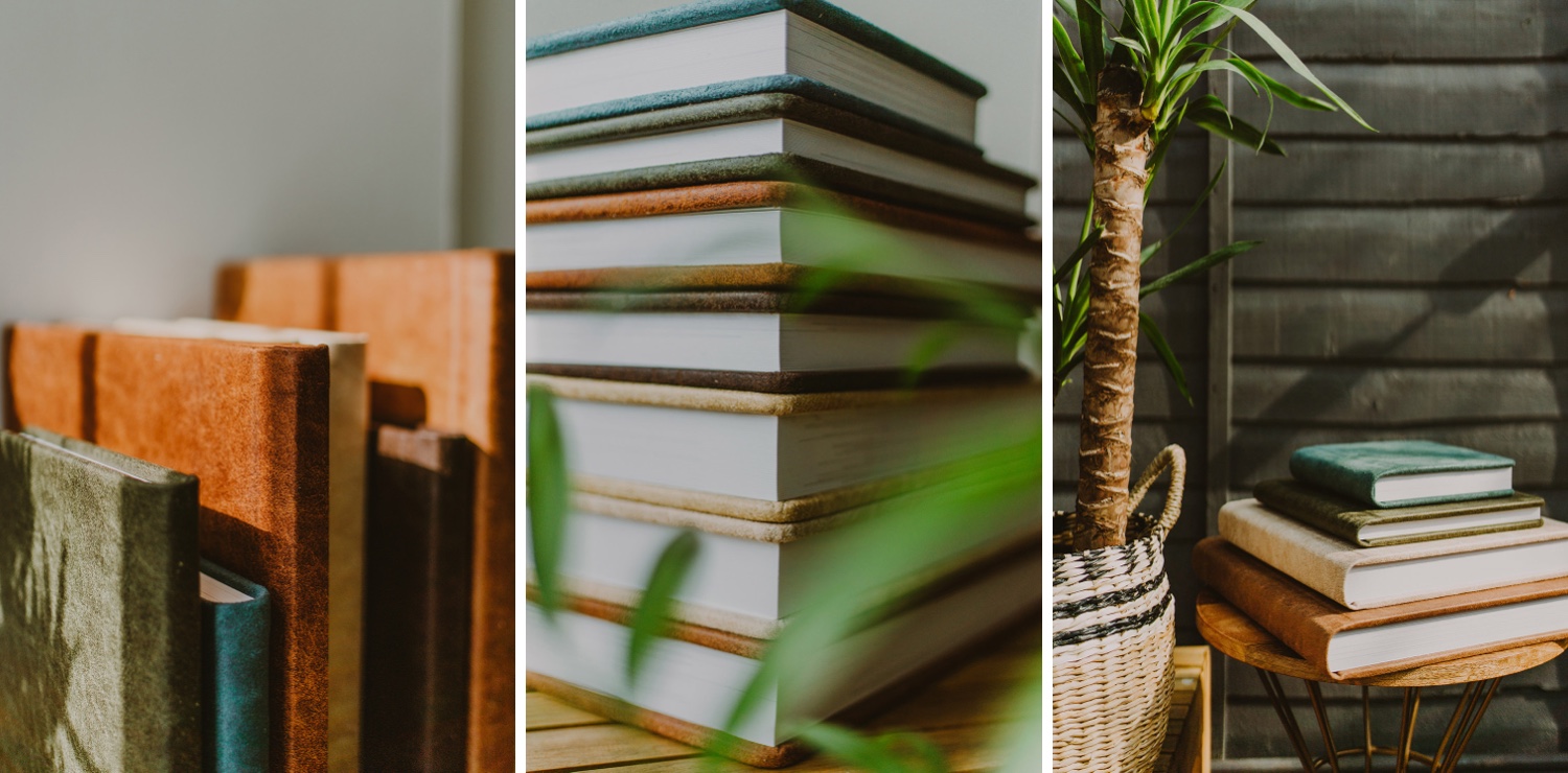 A stack of books on a wooden table next to a potted plant.